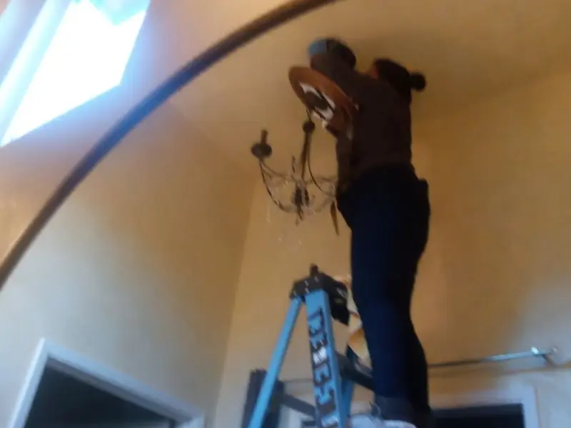 Electrician installing a chandelier in a Argyle residence